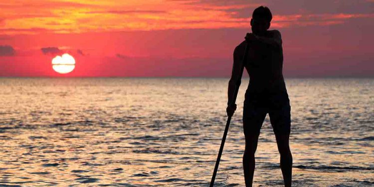 Man on paddleboard in the ocean during sunset