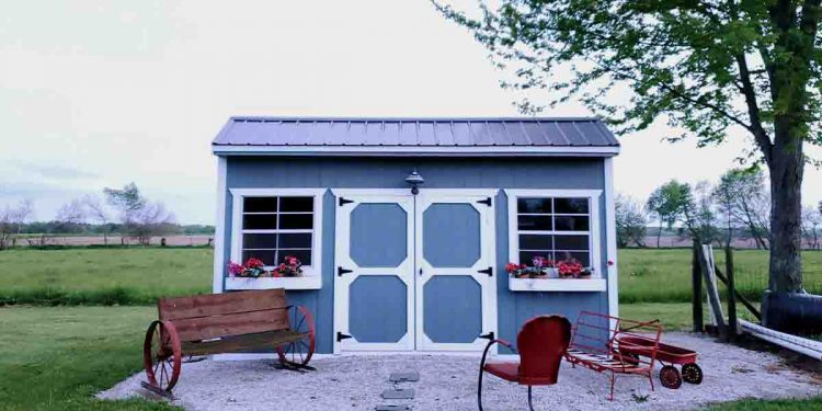 Blue garden shed with white trim in a rock garden