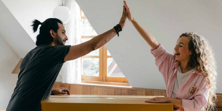 Couple high fiving over cardboard box