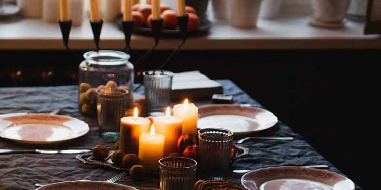 Table decorated for a dinner party with green tablecloth and candles.