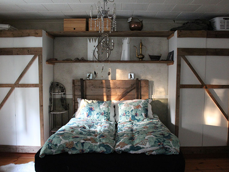 Bedroom with shelves and wooden headboard behind bed