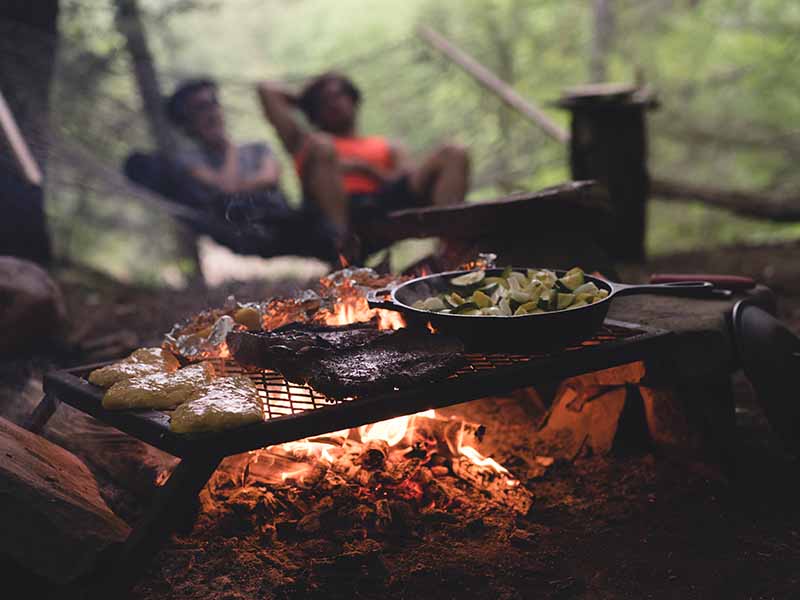 Camping cook gear and skillet over campfire