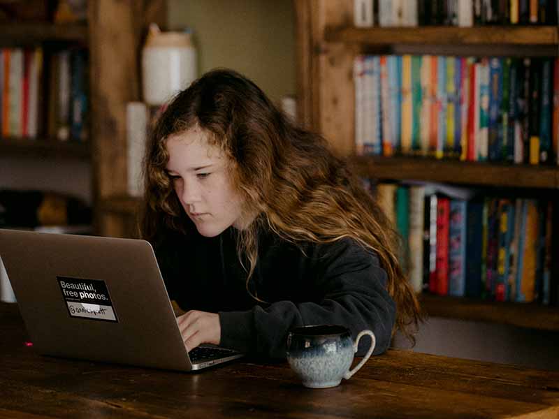 Girl typing and searching on a laptop at a desk