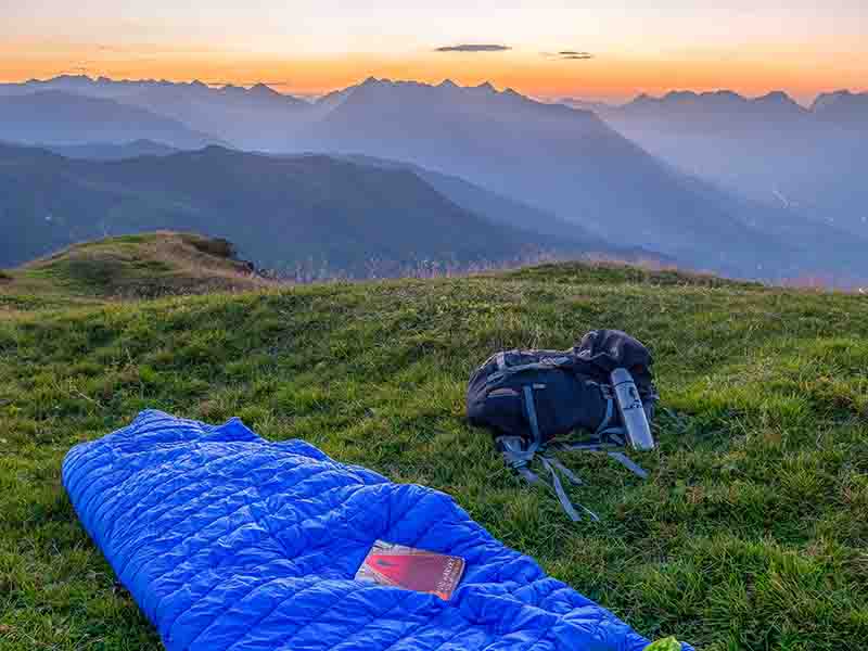 Blue camping bag on grassy hill