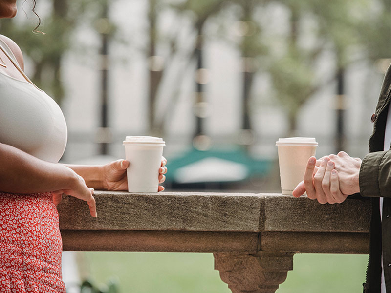 Two people with coffee outside.