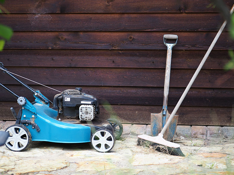 Blue push mower, broom, and a shovel.