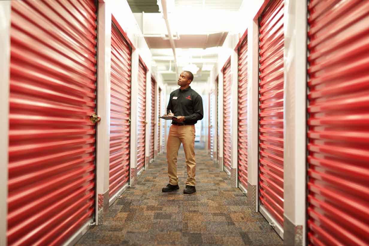 store manager walking through hallway inspecting storage unit doors