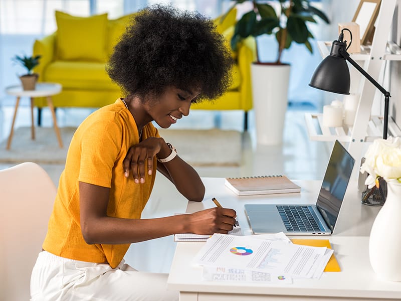 black woman in yellow blouse working at a computer