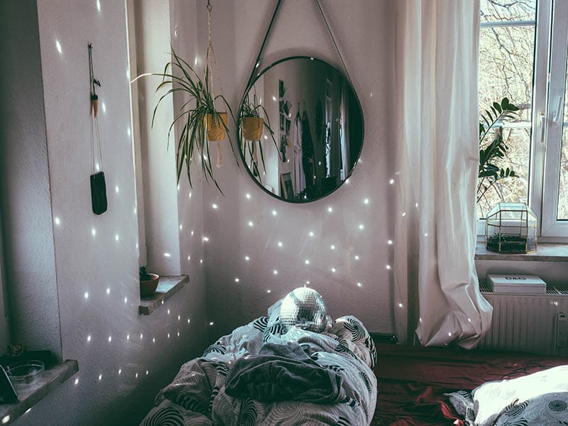 bed room with hanging mirror and hanging plant