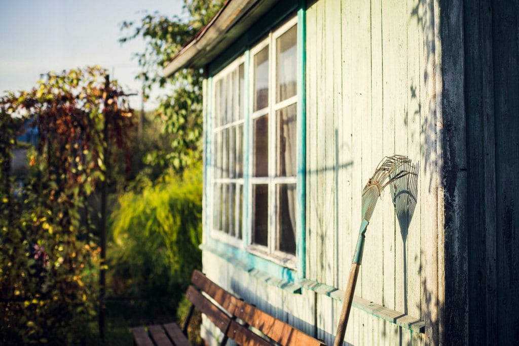 A rake leaning on a shed