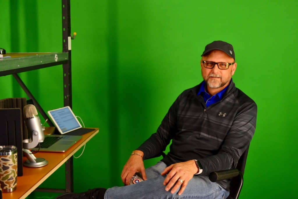 Cliff S. sitting inside his storage unit in front of a green screen