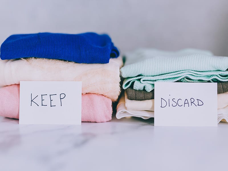 Stack of clothing with a sign for Keep and a sign for Discard