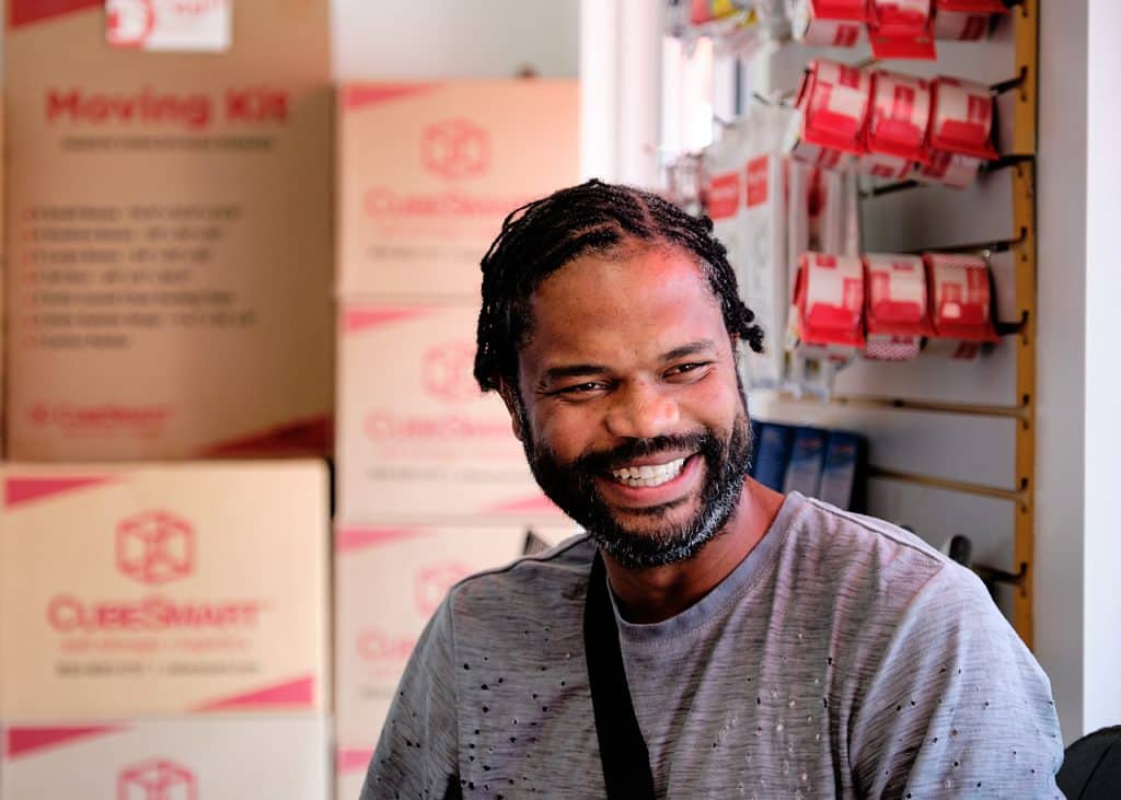 CubeSmart customer Rod Hart smiling in front of moving boxes