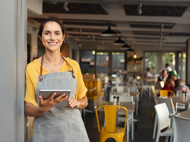 women in yellow shirt holding tablet in restaurant