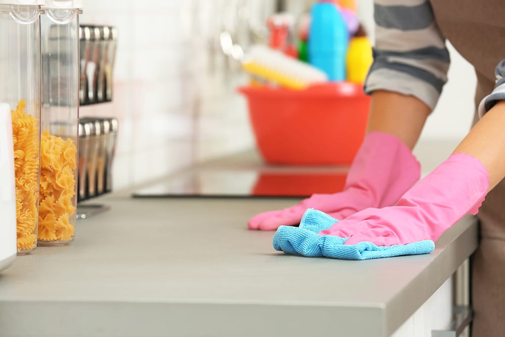 person in pink gloves cleaning kitchen counter