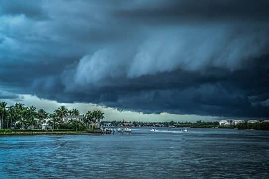 dark storm clouds hovering over the water and the shore