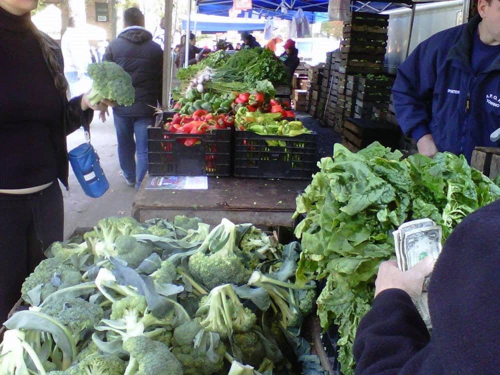 people buying from a produce stand at Jackson Heights Greenmarket in NYC