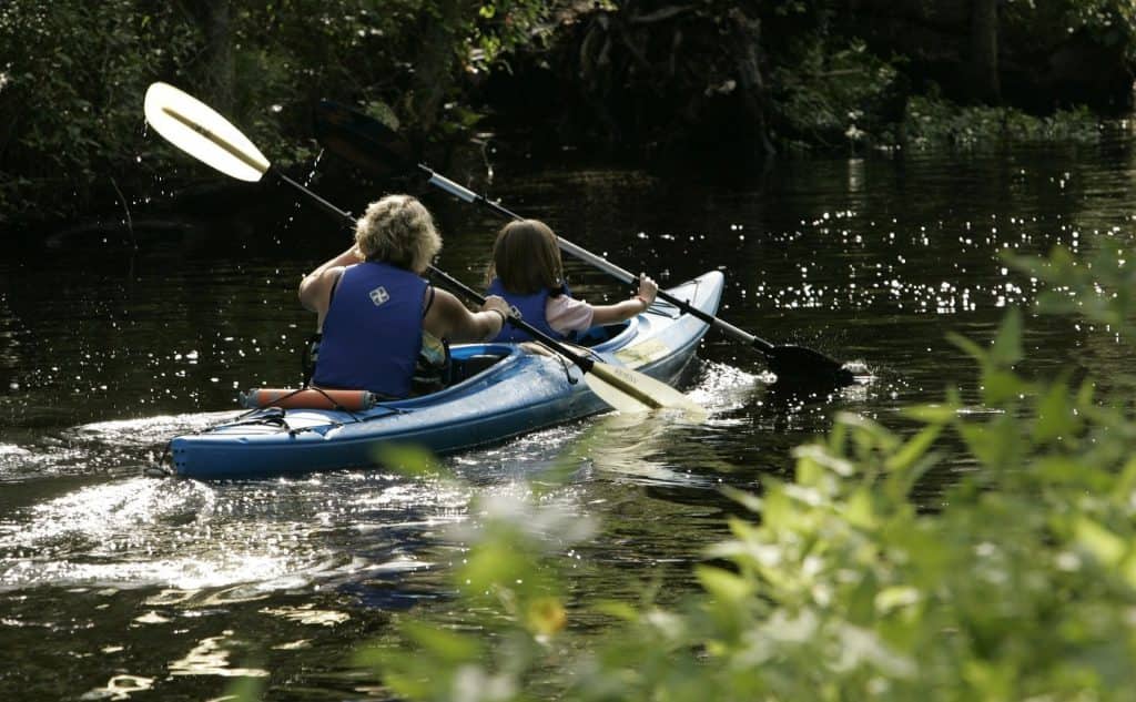 two people in a kayak kayaking down a river