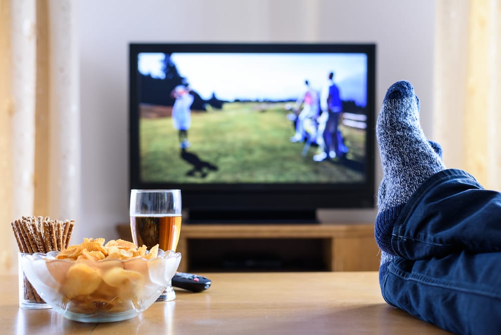 TV watching (golf game) in living room with feet on table