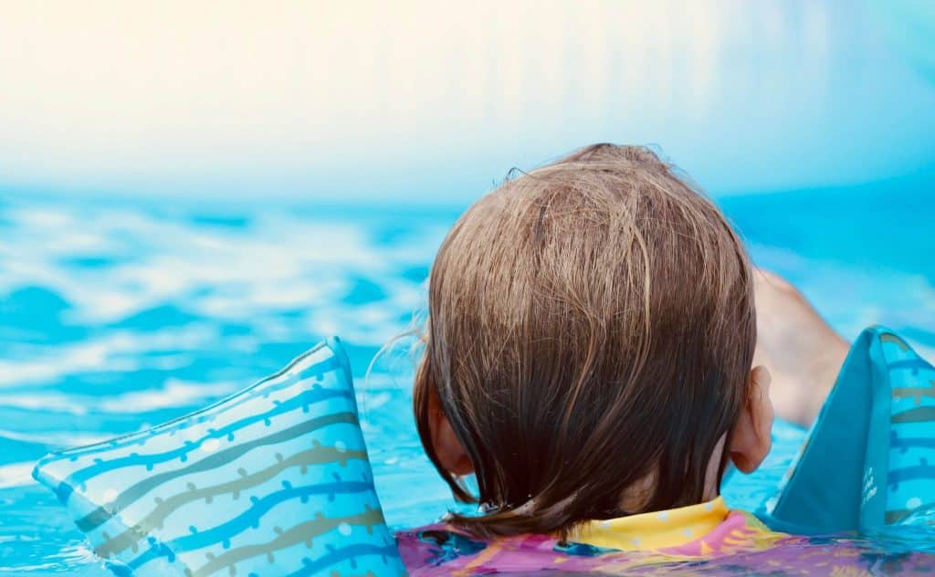 child swimming in pool with floats on